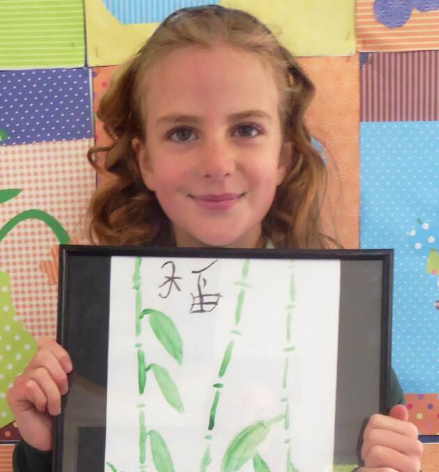 Riley King with her artwork showing bamboo trees.
