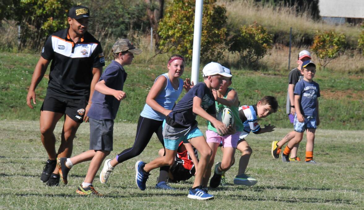 LEARNING FROM THE BEST: Cooper Wilson takes the ball up in a training drill with West Tigers players at Guyra Junior Rugby League's registration day. 