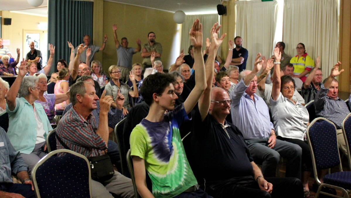 RESIDENTS RALLY: Guyra residents raise their hands in support of a street rally in protest at the forced merger of Guyra Shire and Armidale Dumaresq councils.