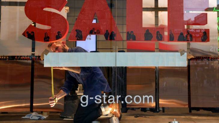 An employee places a sales sign in the window of a G-Star Raw Denim SL fashion retail store on Oxford Street. Photo: Chris Ratcliffe