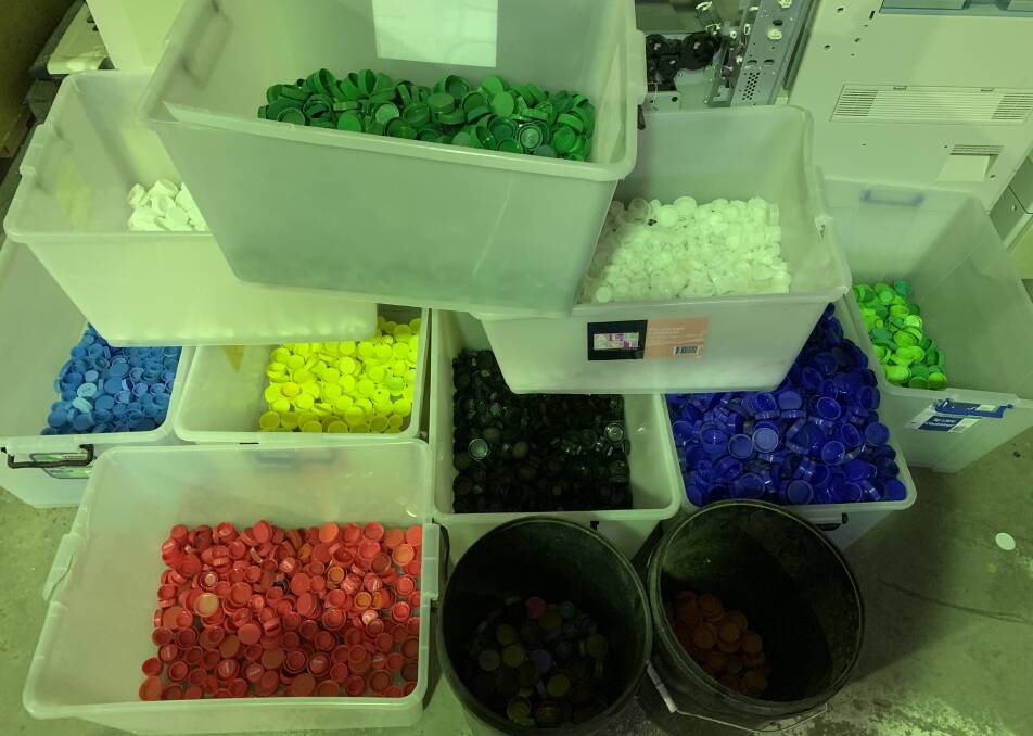 Tubs of the plastic lids sorted into colours ready for shredding, melting and reinventing.