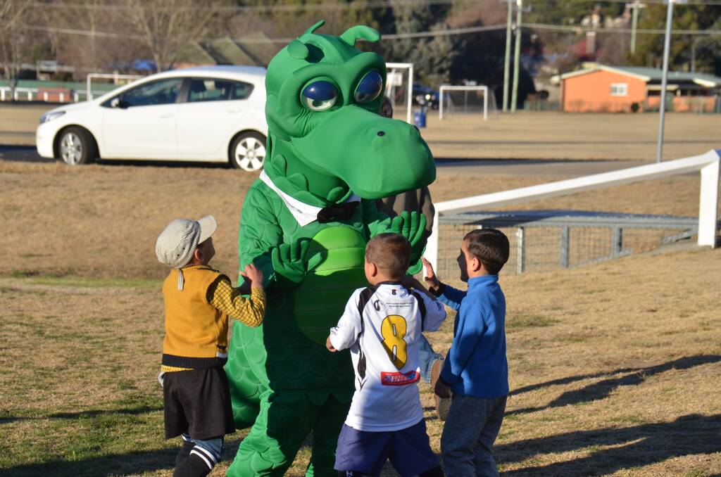 ON THE FIELD: Happy the St George Bank dragon welcomes refugee children to Armidale and on to the soccer field. 