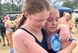 Isabella Henderson, first out of the water for TAS, is given a congratulatory hug by  swimming captain Prudence Black, who was second girl home for TAS. 