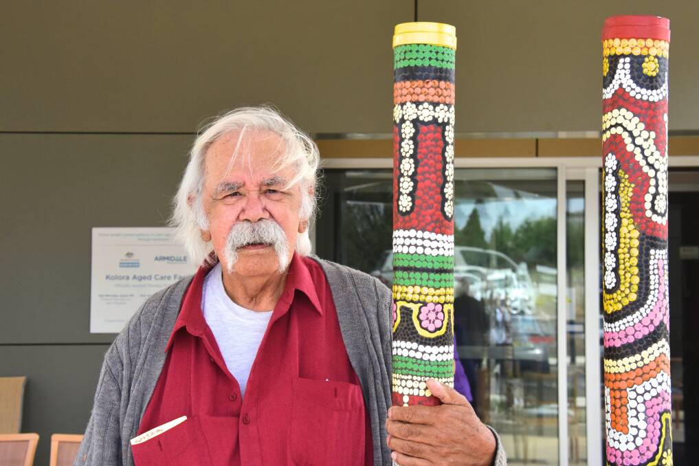 ARTIST: Brian Irving clasps one of his totem poles outside Kolora. Picture: Nicholas Fuller