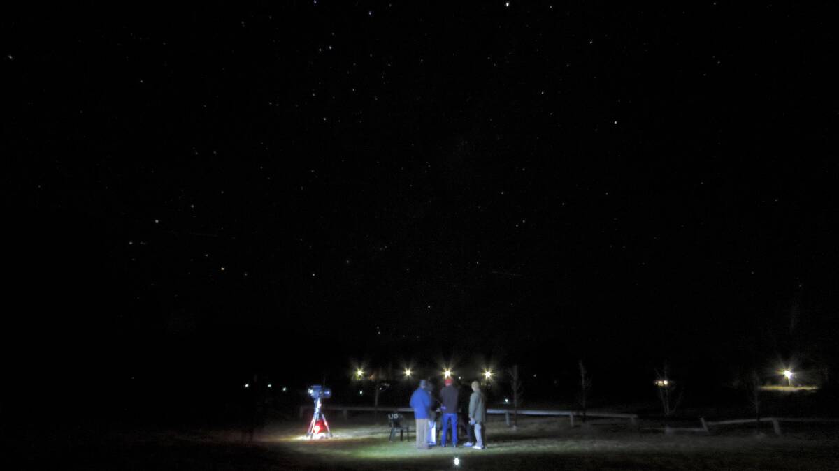 STAR GRAZING: Lachlan Ward teaches the 'grown ups' about astronomy as they gather around his telescope. The constellation Scorpio rises to east of Ben Lomond village, with the village street lights just above the heads of the 'observers'. Photo: Supplied by Beth White