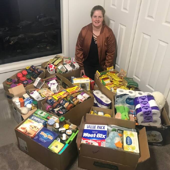 BOXES FOR FARMERS: Rotary Club member Briana Merritt with some of the produce donated by Guyra residents for farmers in need.