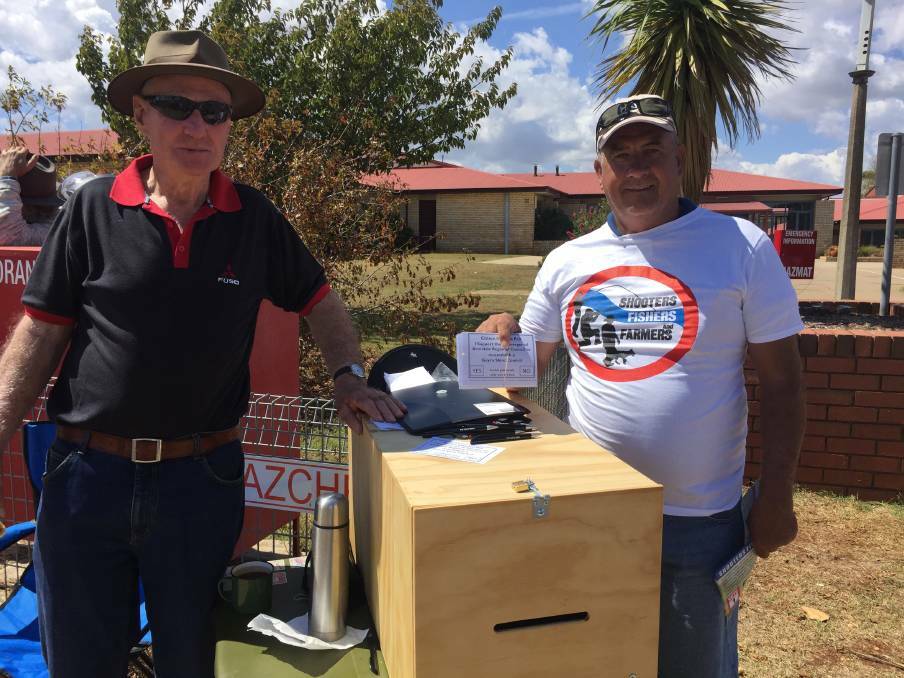 COLLECTING VOTES: Barry Sweeney and Wayne Mendes (Shooters, Fishers and Farmers Party), with the survey box outside the Guyra Central School on Saturday. Photo: Nicholas Fuller

