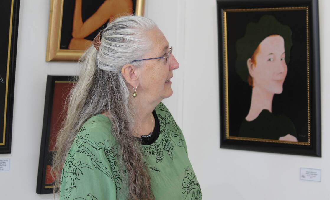 Tess Cullen admires Stewart MacDonald's "Girl In A Green Beret", just one of his works on display at the Armidale Art Gallery.