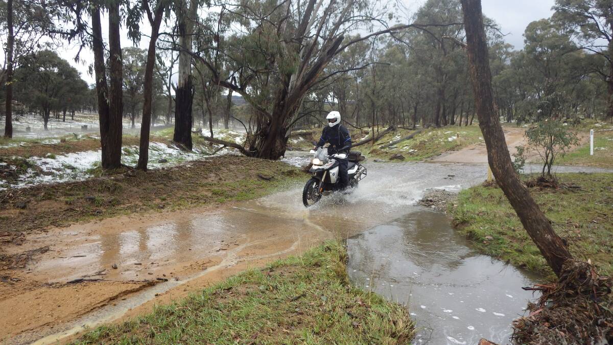 Stewart Lowden rides over a raised creek after the worst of the storm.